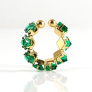 Gold earring with green gemstones on a white background