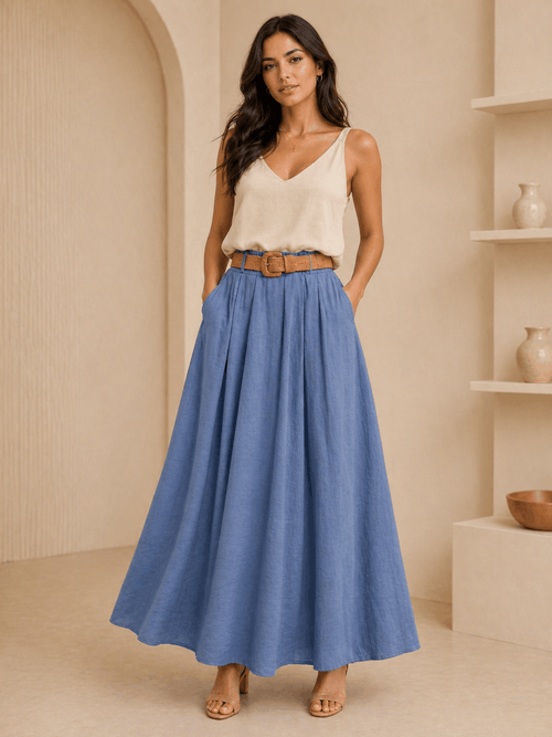 Woman wearing a white top and blue skirt in a beige room.