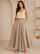 Woman wearing a white top and beige skirt in a neutral setting