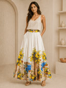 Woman wearing a white top and a long floral skirt with a scenic print in a neutral setting.
