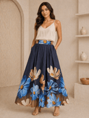 Woman wearing a white top and navy floral skirt in a neutral setting