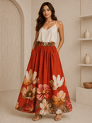 Woman wearing a white top and red floral skirt in a neutral setting