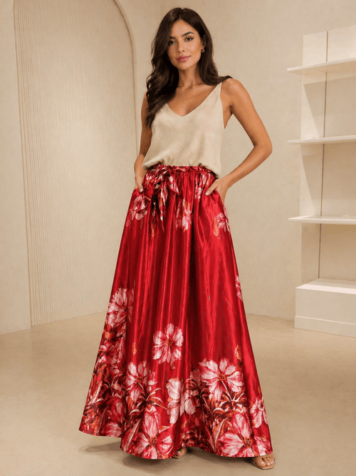 Woman wearing a red floral skirt and white top in a neutral setting