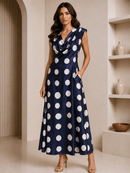 Woman wearing a navy blue dress with white polka dots in an indoor setting.