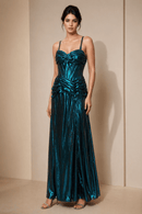 Woman wearing a teal evening gown against a beige wall