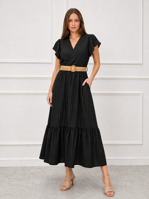 Woman wearing a black dress with a belt against a white wall